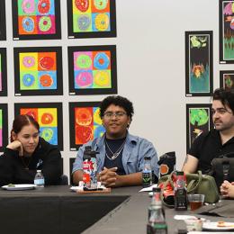 students speaking in front of a wall of art