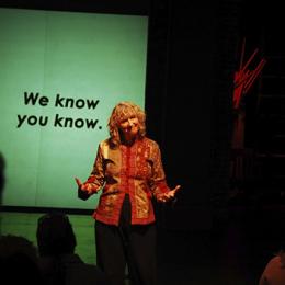 Woman standing in front of a projector screen teaching.
